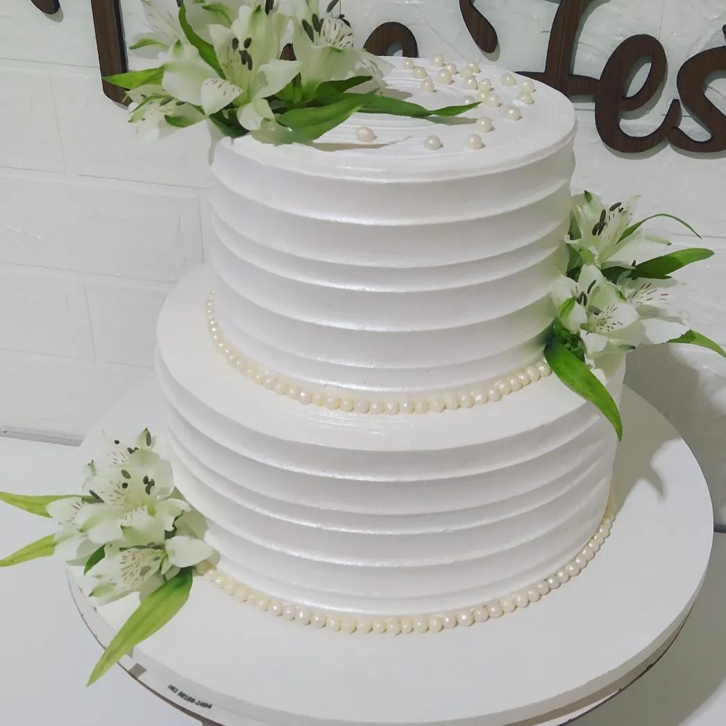 Bolo branco de dois andares decorado com flores brancas e pérolas